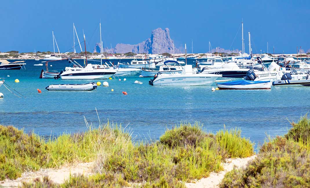 Schiffe im S'Estany des Peix auf Formentera, im Hintergrund Es Vedrà von Ibiza